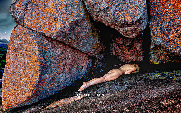Fine art color nude taken in the Texas hill country of a model laying prone upon colorful pink granite.