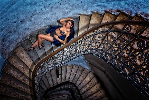 Fashion photo of a woman in lingerie posed on a winding European staircase.