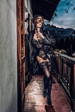 Lingerie -Glamour photo of a woman on a balcony in Cortina, Italy,, holding a Venetian stick mask.