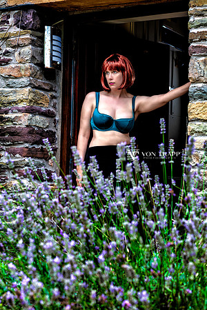 Lingerie glamour photo of a hot redhead, wearing lingerie, posed standing in the open door od a stone cottage in Wales, UK.